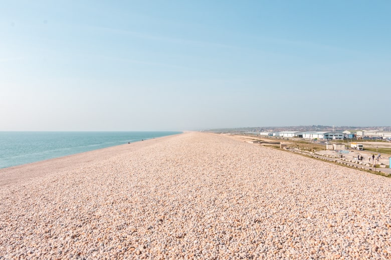 Chesil Beach with sea on the left, and industrial buildings in Portland on the right - best beaches near Weymouth