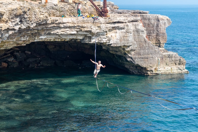 Guy walking on a rope by the Cave Hole on the Isle of Portland - things to do in Weymouth