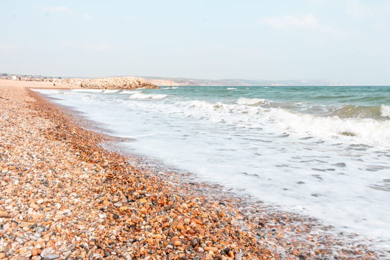 Shingle part of the Weymouth Beach with Bowleaze Cove in the background - best beaches near Weymouth