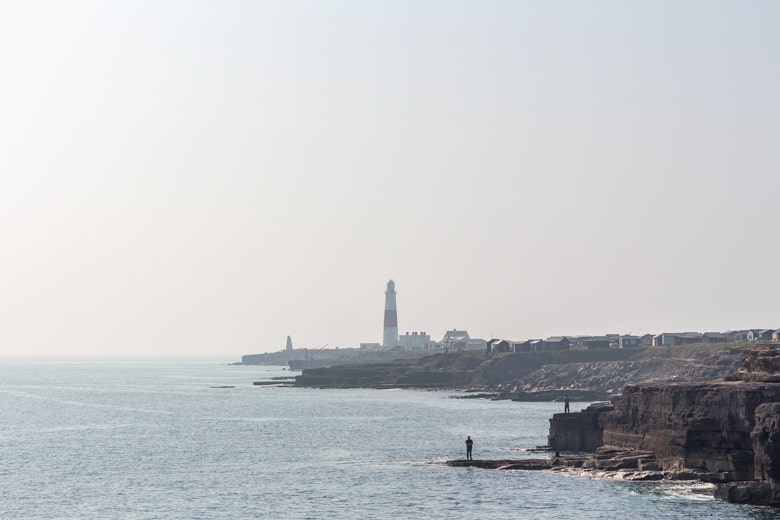 View of the Portland Bill Lighthouse towering above cliffs and the sea - weekend break in Weymouth